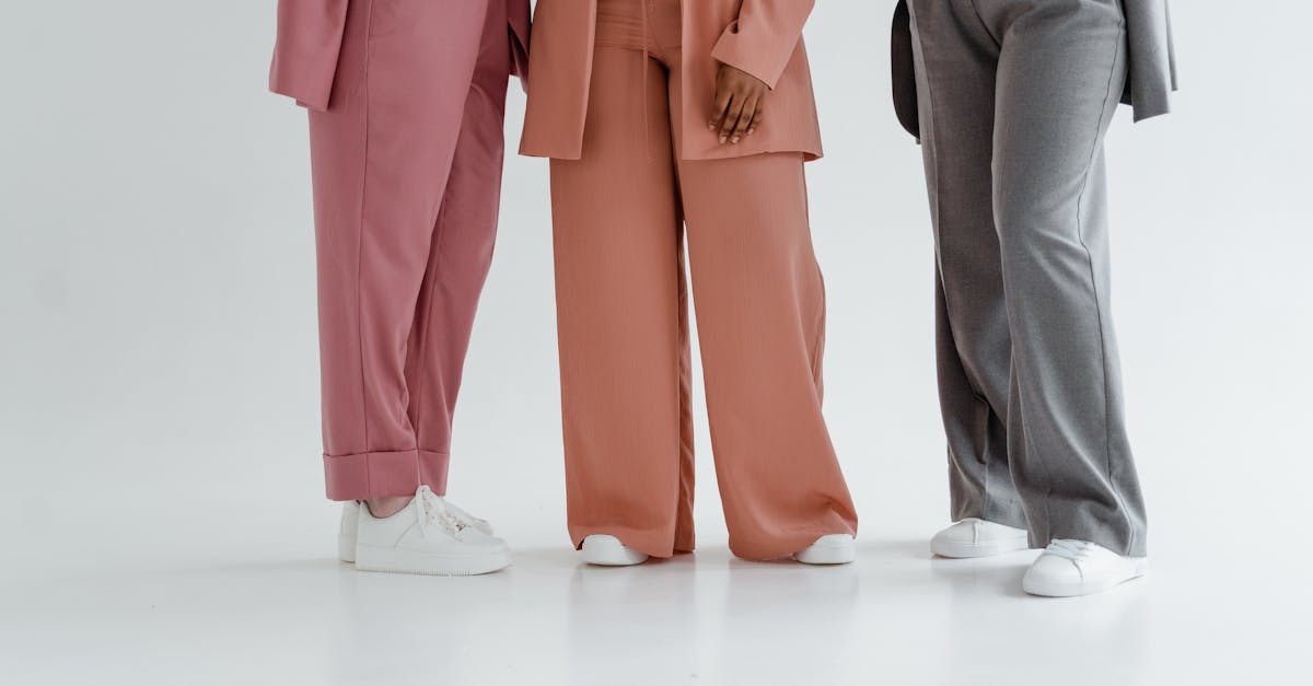 A stylish studio shot showcasing three colorful trouser styles with white sneakers on a clean background.